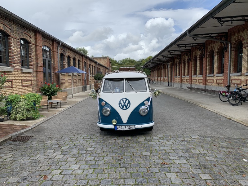 Bulli mit Blumenschmuck im Innenhof einer Hochzeitslocation
